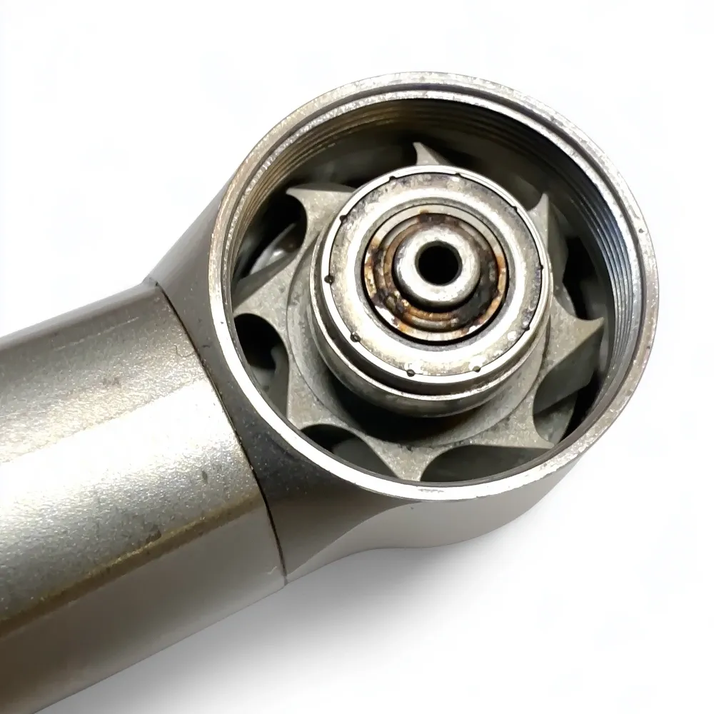Eine geöffnete Dentalturbine mit einem defekten rostigen Rotor im Turbinenkopf.